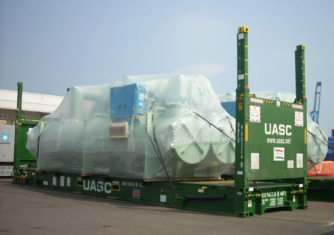 Flat rack container carrying wrapped out-of-gauge industrial cargo