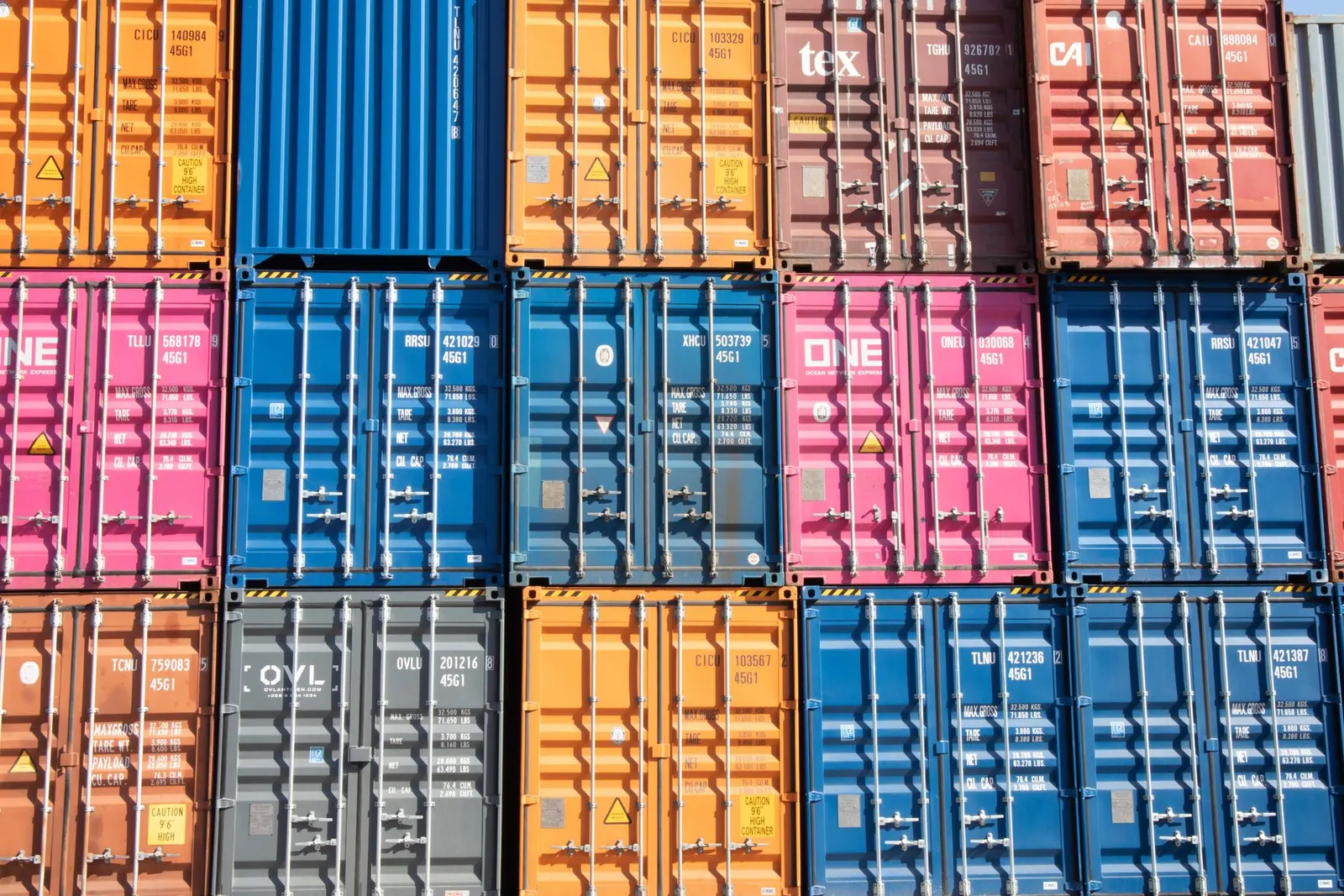 Rows of shipping container cargo doors and locking bars in different colours