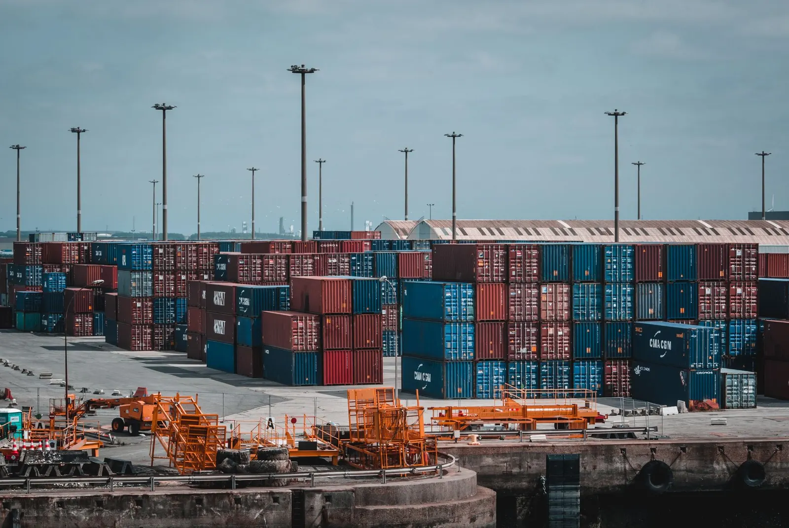 Multi-coloured 20FT and 40FT shipping containers stacked at a port container terminal
