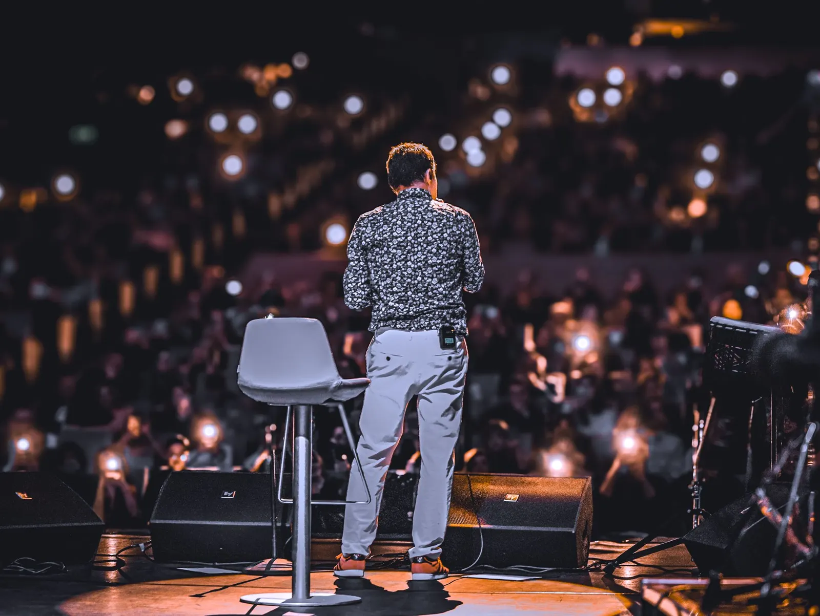 Speaker on stage facing a large audience at a corporate event