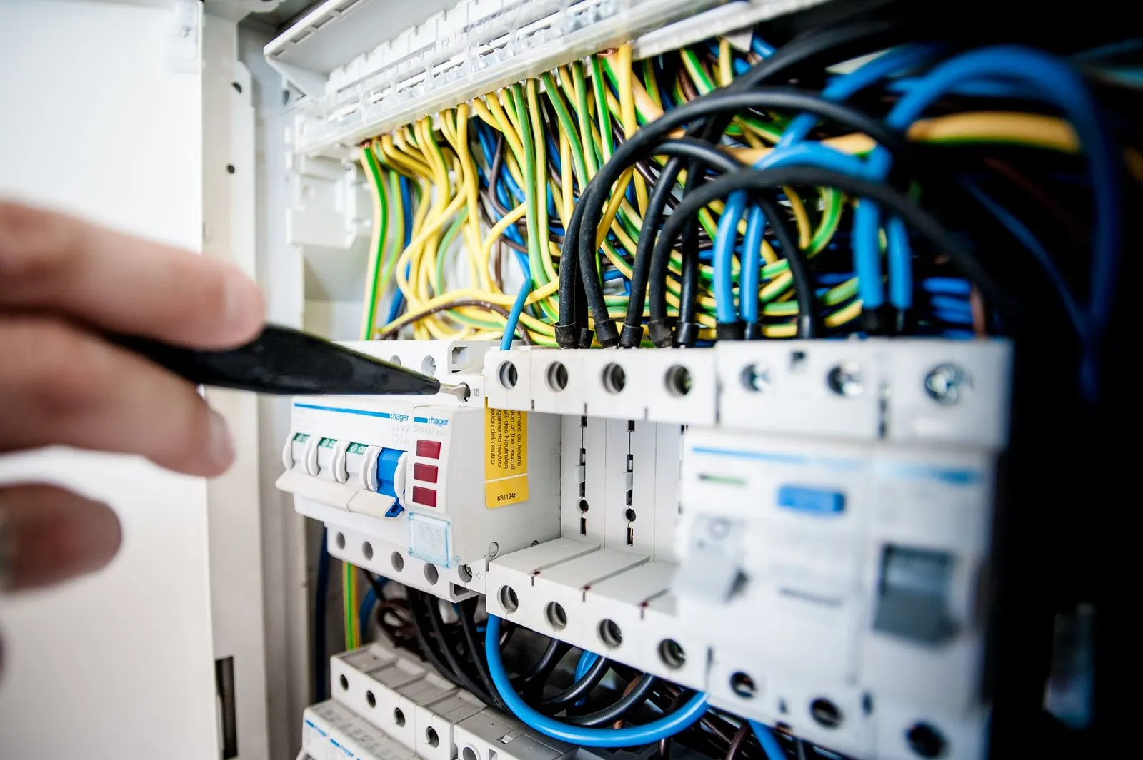 Electrician working on a switchboard with cables and breakers