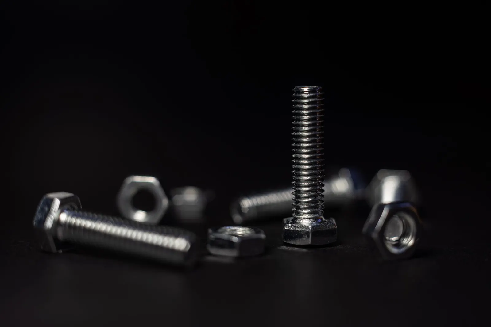 Steel bolts and nuts on a dark background