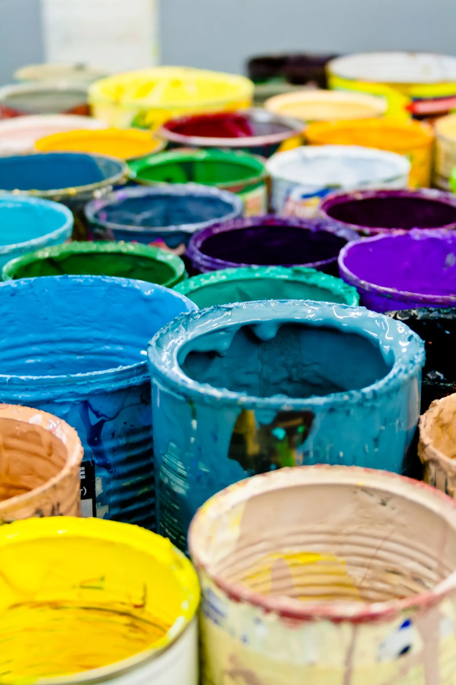 Open buckets of industrial paint in several colours
