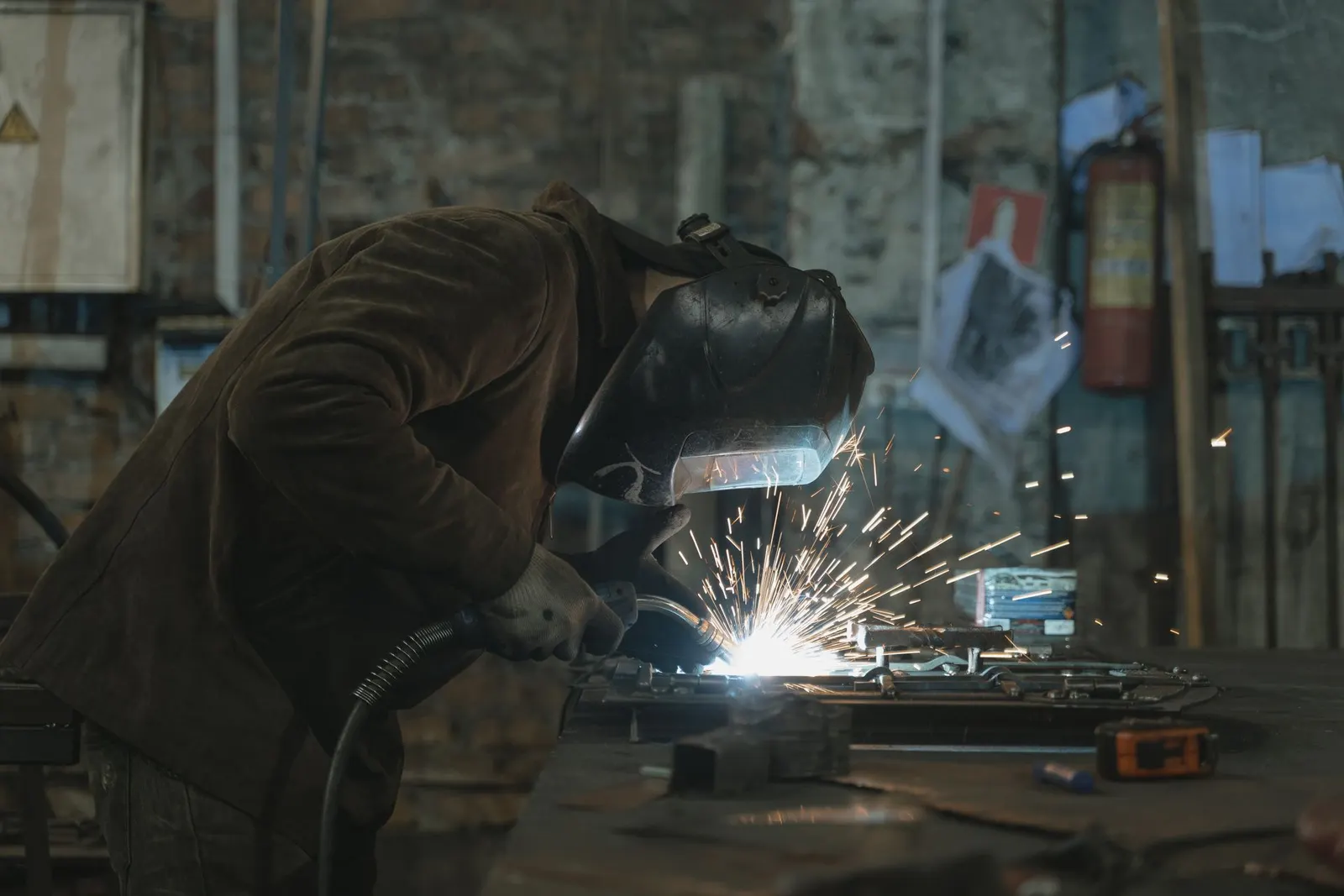 Welder in a protective mask fabricating metal with sparks